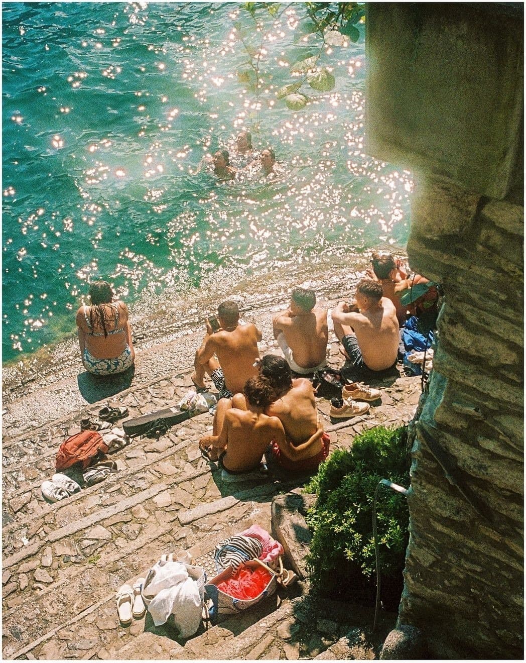 Students relaxing on stone steps by the water on a study-abroad weekend